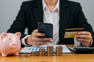 Foto: Mann mit Smartphone, Bankomatkarte, Sparschwein und Münzen